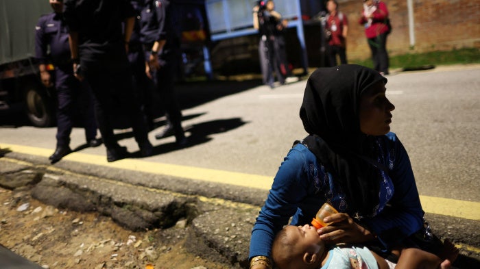 A Rohingya refugee feeds a child in front of the office of the UN refugee agency in Kuala Lumpur, Malaysia, July 27, 2026. 