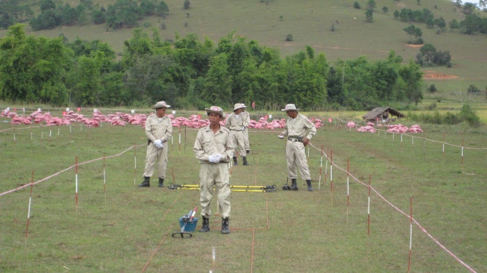 Red sandbags cover unexploded submunitions awaiting destruction near a school in Xiang Khouang Province, Laos