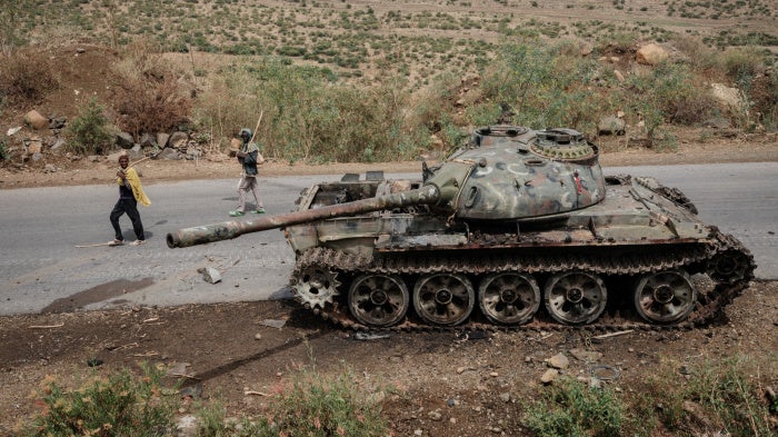Farmers walk past an alleged Eritrean army tank abandoned in Dansa, southwest of Mekele in Tigray region, Ethiopia, June 20, 2021. 