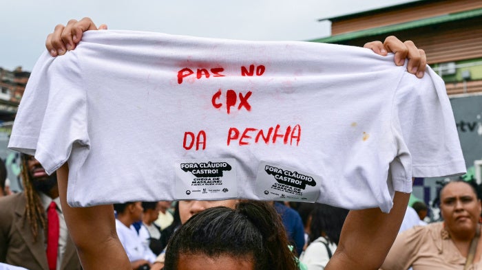 A woman holds up a shirt with a message in Portuguese on it during a protest