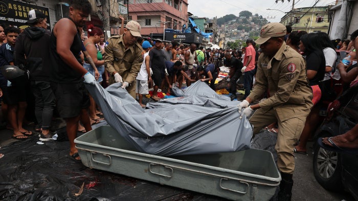 Firemen lift bodies recovered from the nearby forest in Saint Luke Square in Complexo da Penha