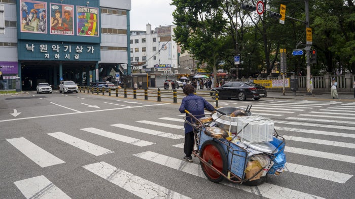 An elderly person pushing a handcart containing fast food supplies in Seoul, South Korea, August 1, 2025.