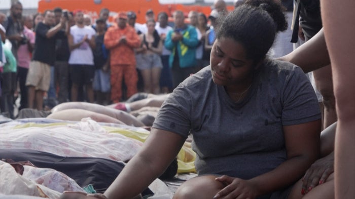 A woman sits among a crowd of people looking down