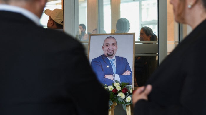 People stand near a framed photo of Guatemalan lawyer and anti-corruption figure Juan Francisco Solorzano Foppa, who died after being shot by unknown assailants on Saturday while visiting a sports center, during his wake at a funeral home in Guatemala City, Guatemala, October 19, 2026.