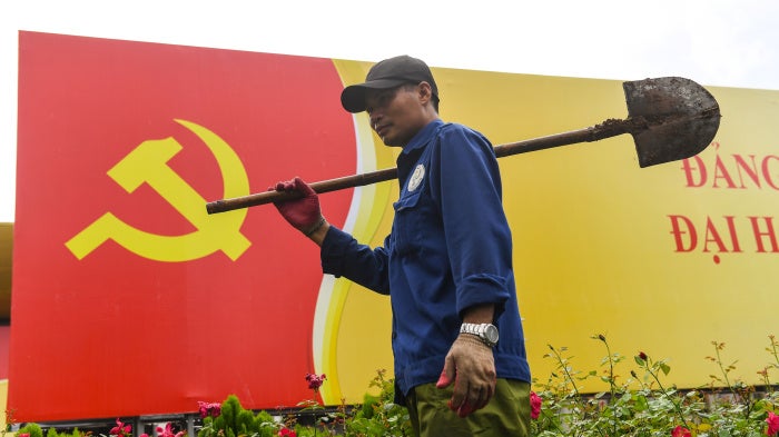 A worker walks past a sign with the Vietnamese Communist Party flag in Hanoi