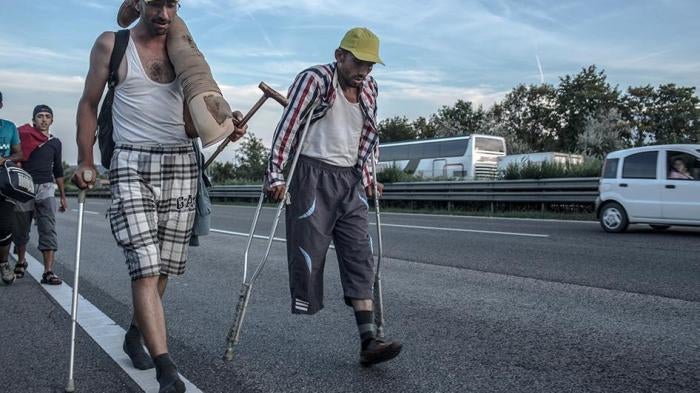 Safi, 30, (right) a Syrian refugee from Aleppo, walks on highway M1 near Budapest, Hungary in an attempt to reach Vienna, Austria by foot.
