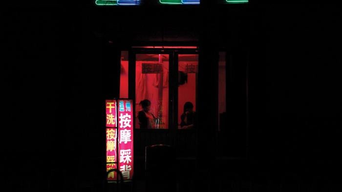 Two women sit near the window of a massage salon on a street in the city of Weifang in Shandong Province on April 20, 2011.