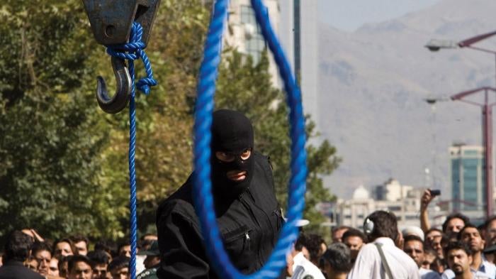 A masked Iranian policeman preparing for the public hanging of a convicted criminal in Tehran on August 2, 2007.