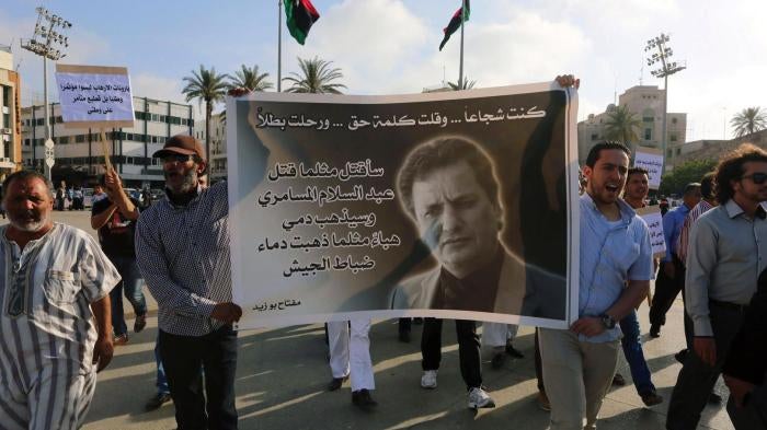 Protesters hold a banner bearing the portrait of Miftah Bouzeid, editor of the weekly newspaper BURNIQ, during a rally in Tripoli’s Martyrs’ Square to protest against his assassination. 