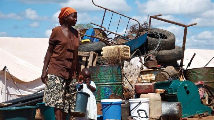  A woman stands in front of a pile of her household property at Chingwizi transit camp, which the government forcibly shut down in August 2014. Hundreds of families lost their property left in the open during their relocation to the camp. March 2014.