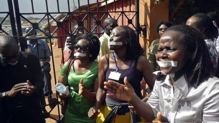 Employees of the Daily Monitor newspaper with their mouths taped shut, sing slogans during a protest against the closure of their premises by the Uganda government, outside their offices in the capital Kampala May 20, 2013. 