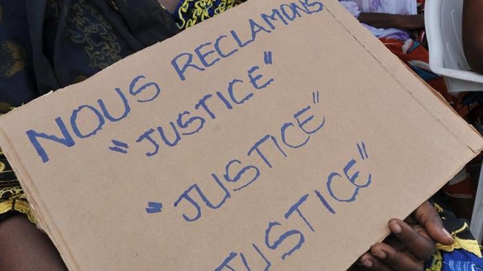 Victims of the 2010-2011 post-election crisis hold placards reading 'We claim justice, justice justice' at a gathering in the Kouassai district of Abidjan on February 28, 2013,