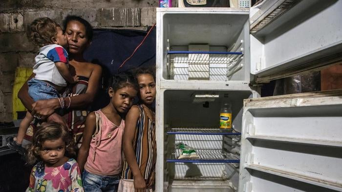 Leidy Cordova, de 37 años, con cuatro de sus cinco hijos en su vivienda en Cumaná, Venezuela, 16 de junio de 2016. Su heladera descompuesta contenía los únicos alimentos que había en la casa: una bolsa de harina de maíz y una botella de vinagre.