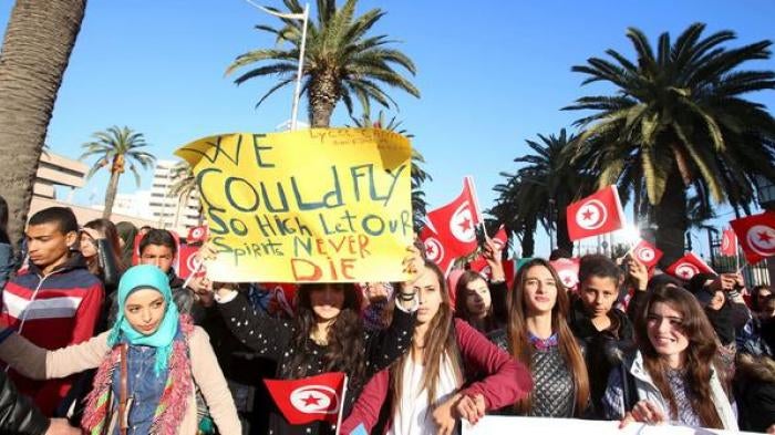 Tunisian students hold flags and placards during a march in memory of 12 presidential guards who were killed in an attack in Tunis.