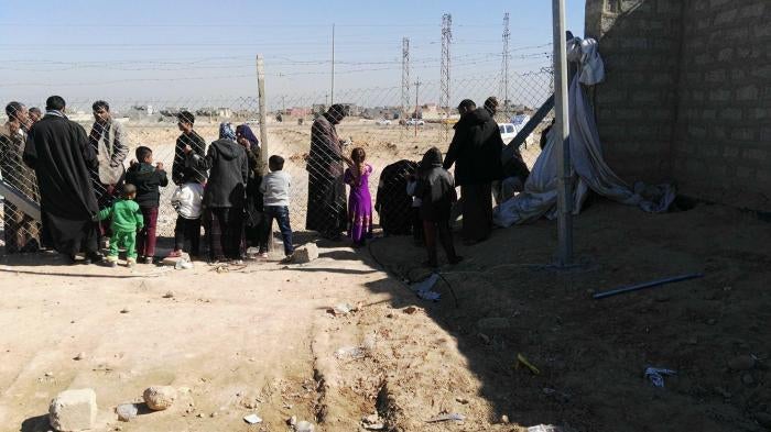Residents of Shahama camp speak with relatives through the camp fence. 
