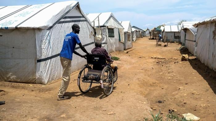 A relative pushes John Biel Dup’s wheelchair through the dirt paths of Protection of Civilians Camp 3 in Juba,. The uneven paths make it difficult for people with physical disabilities to move around the camps..