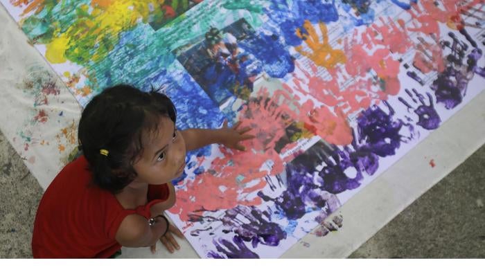 A girl covers anti-LGBT messages in rainbow handprints during a Pride rally in Manila on June 27, 2015. 