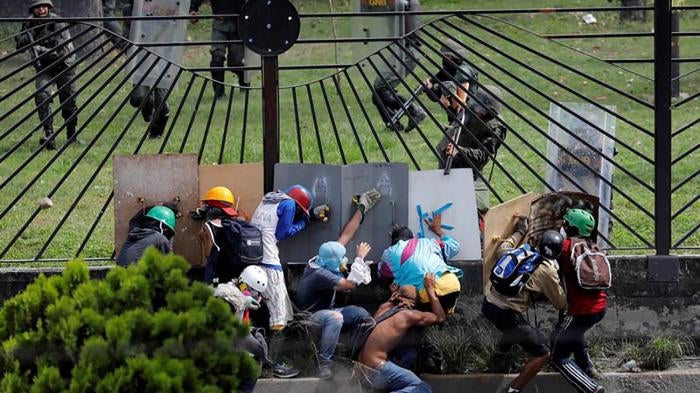 Demonstrators clash with riot security forces at the fence of an air base while rallying against Venezuela's President Nicolas Maduro in Caracas, Venezuela.