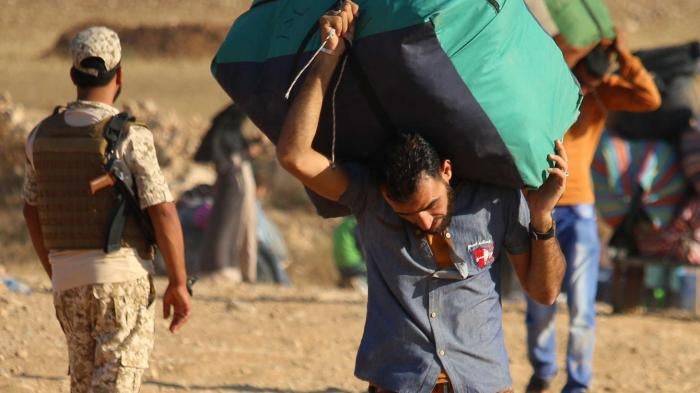 لاجئون سوريون يحملون متعلّقاتهم أثناء العودة إلى سوريا بعد عبور الحدود الأردنية قرب بلدة نصيب، في محافظة درعا الجنوبية. 29 أغسطس/آب 2017.