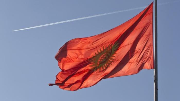 An airplane trace is seen behind a Kyrgyzstan national flag fluttering in a central square in Bishkek March 11, 2013.