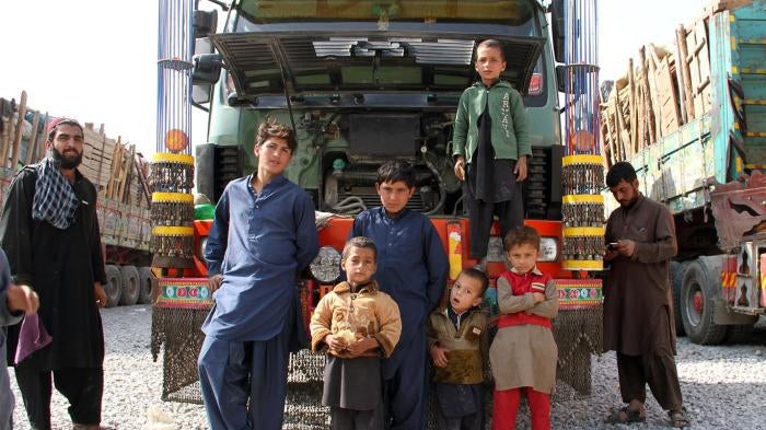 An Afghan refugee family forced out of Pakistan stands by a hired truck laden with their possessions after an overnight journey, October 2016
