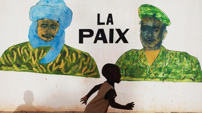 A boy in Timbuktu runs in front of a mural that reads “Peace,” a few days before the July 2013 presidential elections in Mali.