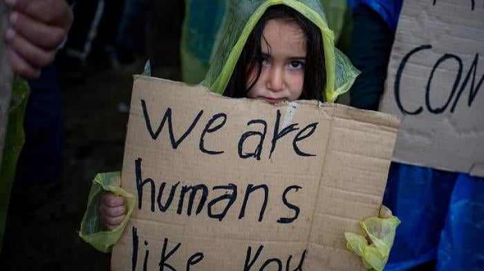  Une fillette tient une pancarte lors d'une manifestation de migrants et de réfugiés bloqués dans un camp provisoire près du village d’Idomeni, en Grèce, le 23 mars 2016.