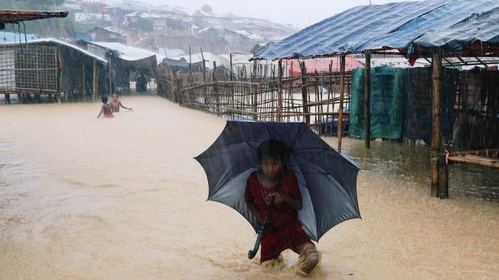 A Rohingya refugee girl walks along the water as the Kutupalong-Balukhali Expansion Camp floods during heavy rain in Cox's Bazar, Bangladesh, July 2018. 
