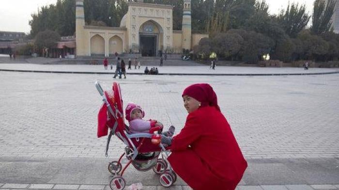 A woman tends to her child near the Id Kah Mosque in Kashgar in western China's Xinjiang region, November 4, 2017.