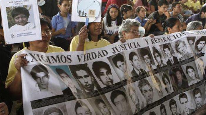 Women carry a banner of photos of missing persons on a day dedicated to the children who went missing during El Salvador's armed conflict in San Salvador, El Salvador, Tuesday March 29 , 2011.