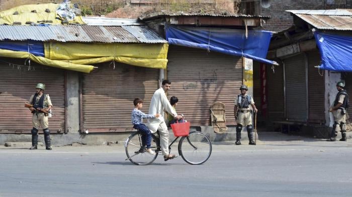 A cyclist rides past paramilitary troops during the curfew in Srinagar, India, August 17, 2019. © 2019 Saqib Majeed / SOPA Images/Sipa USA via AP Images