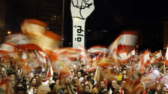 Anti-government protesters wave Lebanese flags during ongoing anti-government protests, in Beirut, Lebanon, November 10, 2019. The Arabic on the fist reads "Revolution."