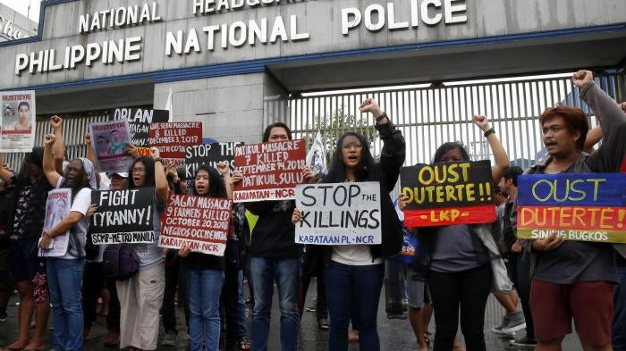 Veiled protesters, mostly relatives of victims of alleged extra-judicial killings, display placards during a protest outside the Philippine military and police camps