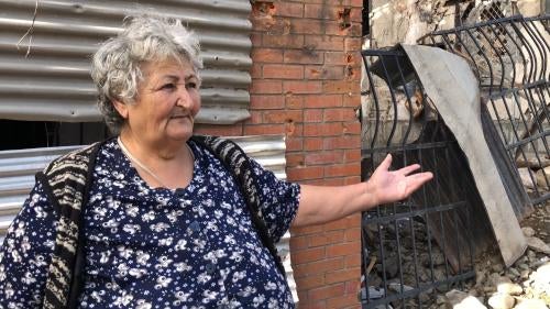 Lady stands in front of a damaged building