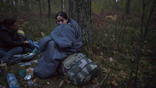 Две женщины и ребенок ютятся в спальных мешках на земле в лесу после пересечения польско-белорусской границы возле Михалово 6 октября 2021 года.