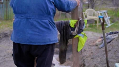 A man puts a cross on a burial site in Ukraine. 