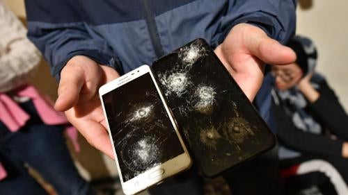 A man displays two broken phone screens
