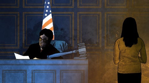 A girl stands in front of a judge in a courtroom