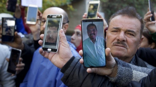 Family members of missing Syrian detainees hold up photos of their loved ones outside al-Mujtahid hospital in Damascus on December 15, 2024.