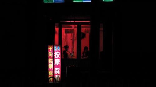 Two women sit near the window of a massage salon on a street in the city of Weifang in Shandong Province on April 20, 2011.