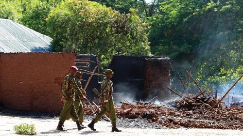 Kenyan police officers walk past the remains of burnt houses after an attack in Kibusu village in Tana River County of the Kenyan Coast on January 10, 2013. Inter-ethnic clashes in 2012 and early 2013 claimed about 180 lives. 
