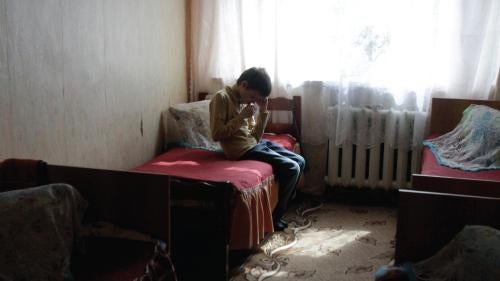 A boy sits in his room at a state boarding school