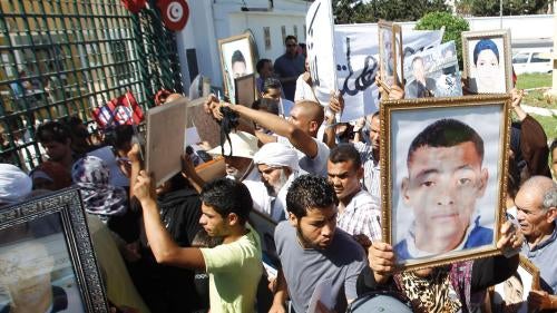 People hold up pictures of relatives who died in protests during the January 2011 revolution, at a demonstration outside a military court in Tunis June 26, 2012.