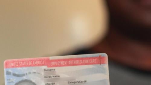A man seeking asylum in the U.S. holds his work authorization card.
