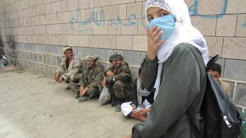 A girl student leaves al-Furadh School at the end of the day. Soldiers relax and chew qat outside the school walls. They lived in third-floor classrooms for several months, students and teachers said.