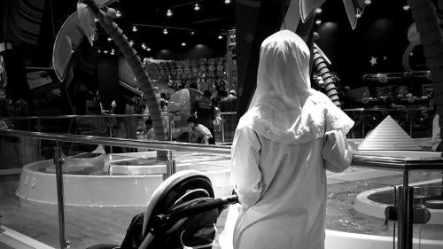 A migrant domestic worker watches over a child playing in the Magic Planet, City Centre Muscat, a shopping mall in Oman.