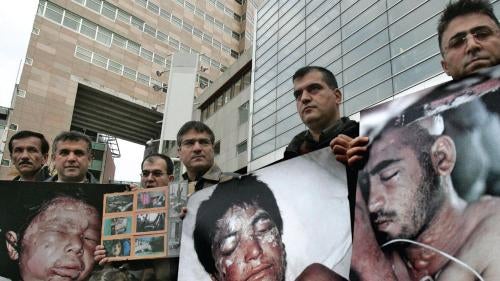 Protesters, with photos of victims killed in chemical attacks in Iraq, gather outside the district courthouse in The Hague on November 21, 2005, as the trial opens against Dutch businessman Frans van Anraat. The court convicted Van Anraat of complicity in