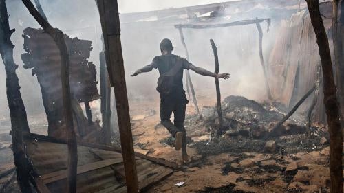 Un homme court parme les décombres d'une maisons pillée et incendiée dans le quartier musulman « PK13 » situé à la périphérie de Bangui, en République centrafricaine, en 2014.