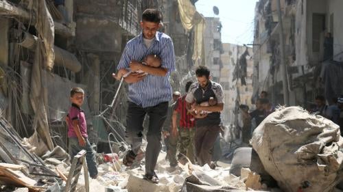Men carrying babies make their way through the rubble of destroyed buildings after an airstrike on the rebel-held Salihin neighborhood of Syria’s northern city of Aleppo, September 2016.