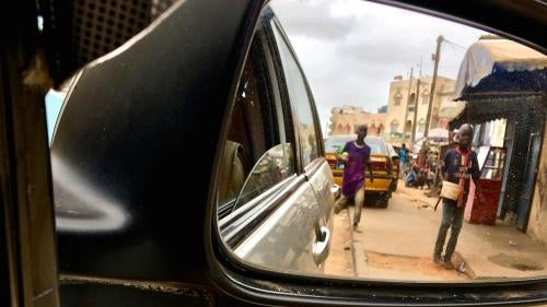 Deux enfants talibés, aperçus dans un rétroviseur, mendient auprès d’automobilistes dans les rues de Dakar, au Sénégal, le 21 juin 2018.  